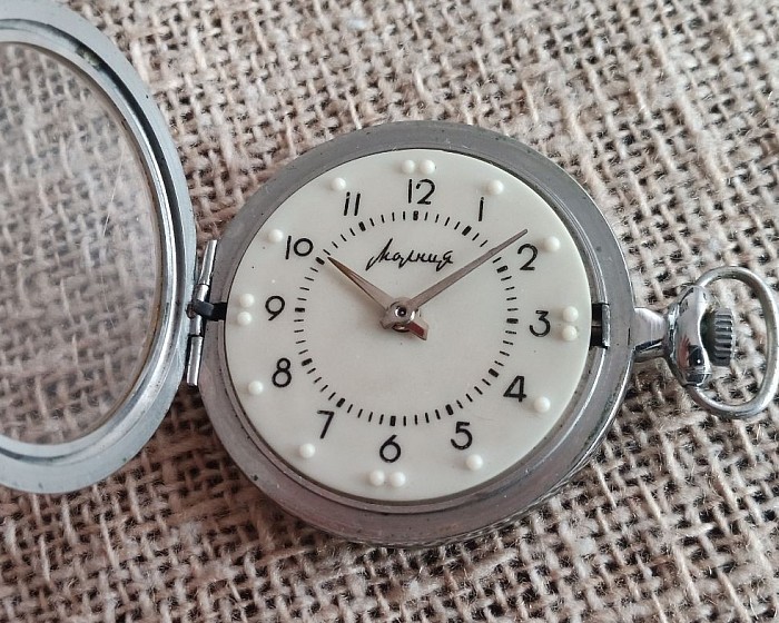 Mołnia, Czelabińska fabryka zegarków, 1-67 (pierwszy kwartał 1967 rok). Ozdobne logo, przeszklone wieczko. Plastikowa tarcza.