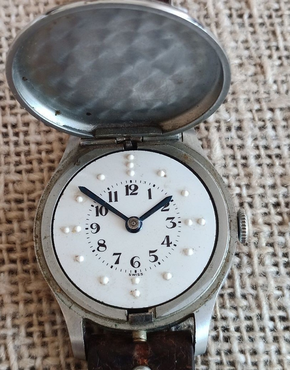 Zegarek dla niewidomych bez nazwy, Swiss made. Wieczko pełne - nie oszklone, na wzór niektórych zegarków kieszonkowych. Stylistyka zegarka wskazuje na lata pięćdziesiąte lub sześćdziesiąte.